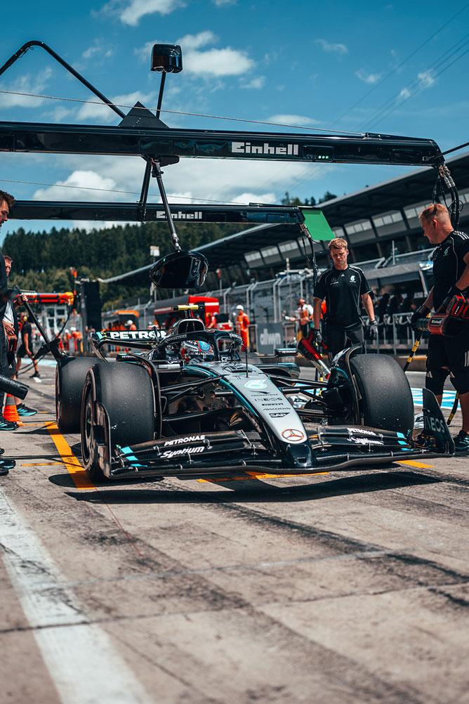 A Mercedes-AMG Formula 1 car is in the pit lane, surrounded by team members under an Einhell garage structure.