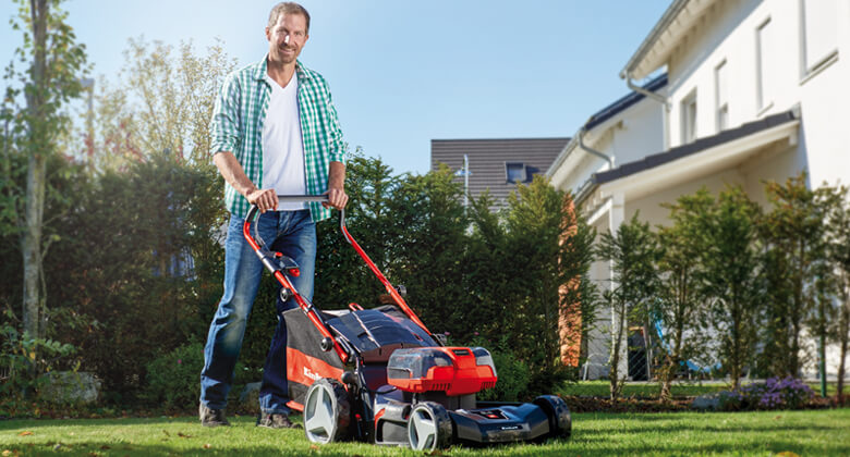 a man mows the lawn with a lawnmower