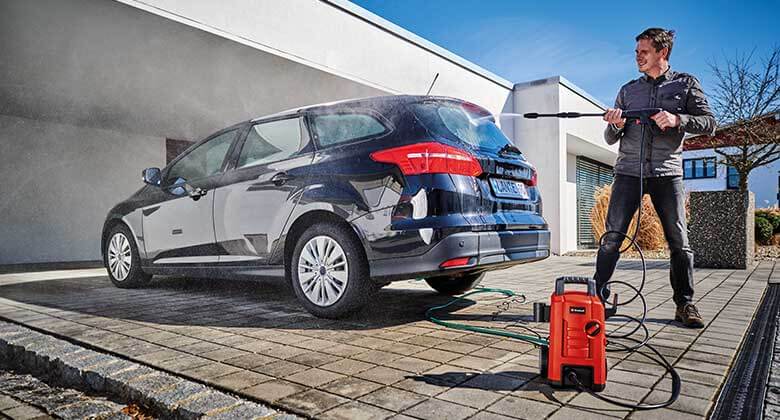 a man cleans his car with a high - pressure cleaner